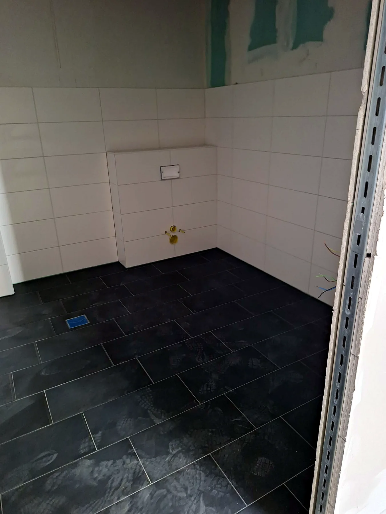 Bad mit dunklem Fliesenboden und weißen Wandfliesen