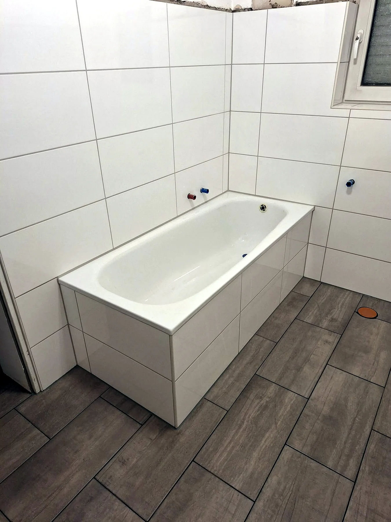 Graue Bodenfliesen im Bad mit eingebauter Badewanne
